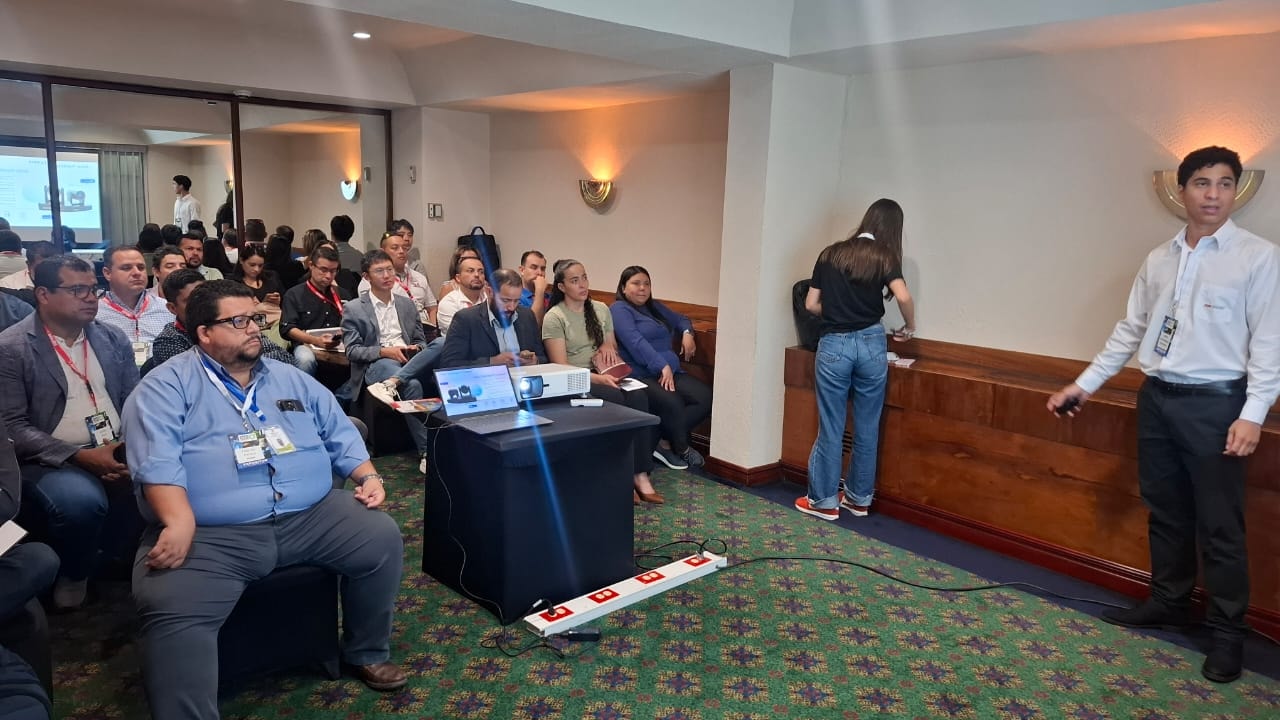 Conferencia técnica con asistentes y presentador en sala del evento