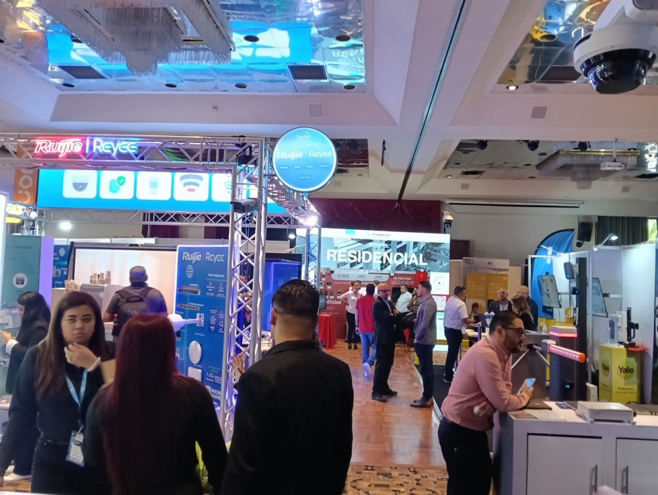 Vista panorámica del piso de exposición con stand Ruijie Reyee y Yale