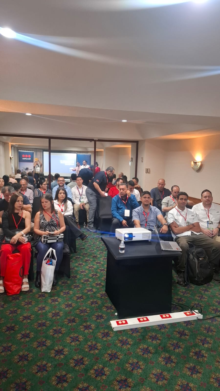 Sala de conferencias llena de asistentes con proyector